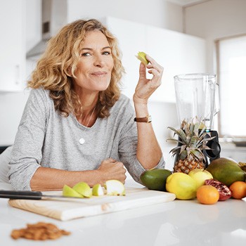 Woman smiling while eating snack in kitchen