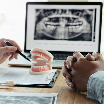 entist showing patient model of teeth with X-ray