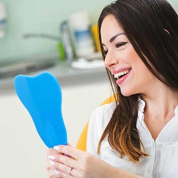 A happy woman admiring her smile in a hand mirror