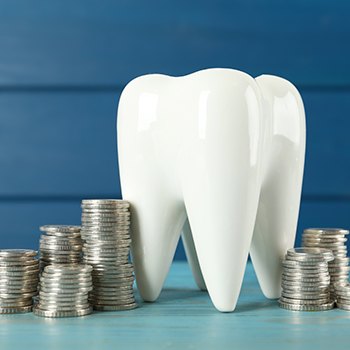 A ceramic model of a tooth surrounded by stacks of coins