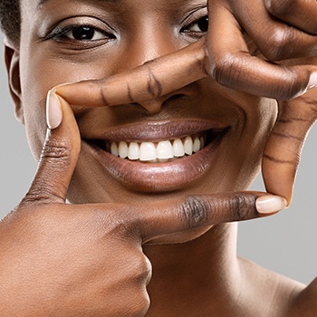 Woman framing her smile with both thumbs and pointers