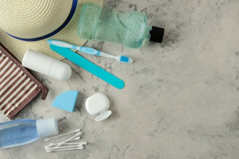 Oral hygiene supplies and sun hat spread out on sand