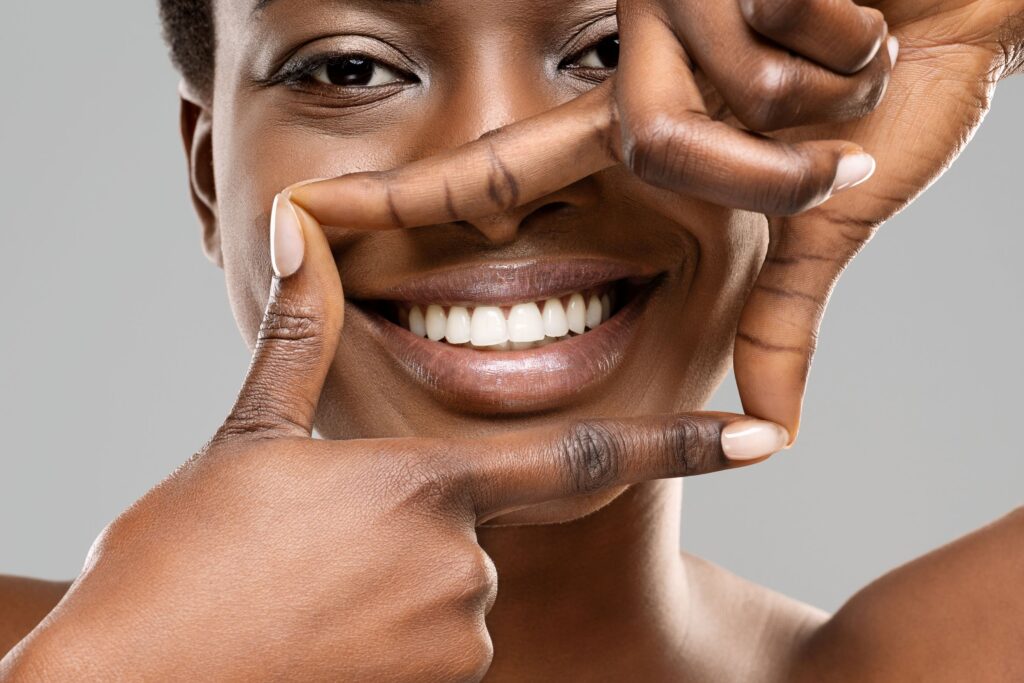 Woman framing her bright white smile with four fingers